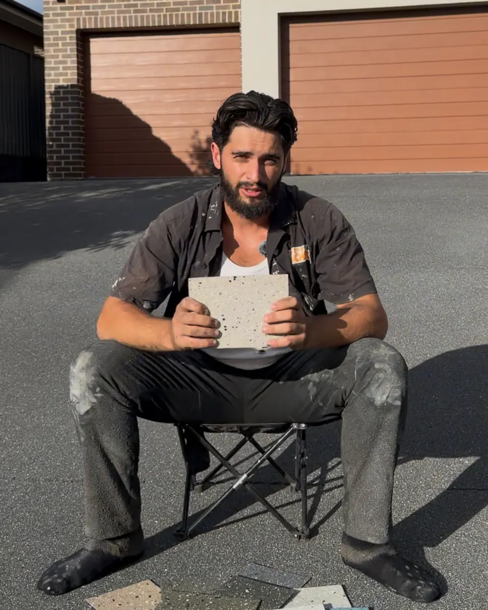 Enrique Dragas on a driveway, holding spray resin sample boards